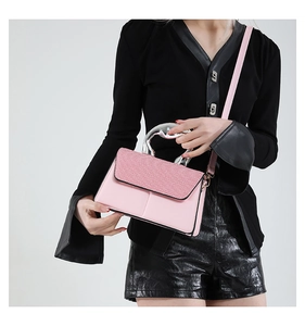 Close-up of pink crossbody bag with woven texture lid and silver wave handle detail