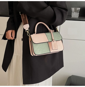 Detail of color-block pink and green shoulder bag featuring a wide embroidered strap