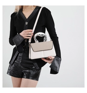 Detail of elegant small square bag featuring a large silver heart-shaped metal handle
