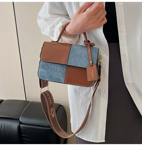 Detail of color-block bag with brown leather, blue denim texture and wide woven strap