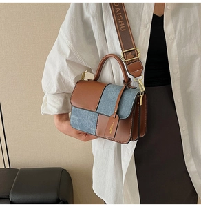 Detail of contrast stitching on leather handbag with adjustable wide logo shoulder strap