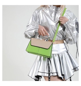 Detail of green and beige contrast crossbody bag with silver metal handle on model
