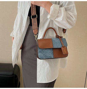 Detail of contrast stitching square bag with wide branded strap and denim texture