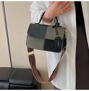 Detail of color-block square bag with white stitching and wide branded strap