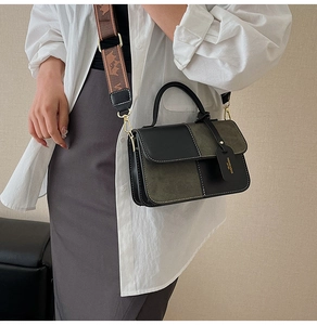 Detail of color-block crossbody bag with textured wide strap and gold hardware accents
