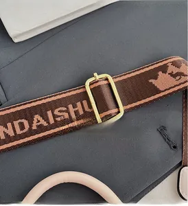 Detailed shot of jacquard shoulder strap with gold metal buckle on a square bag