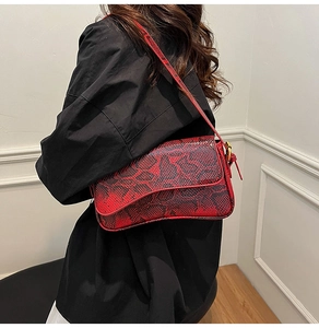 Side view of a vintage snake pattern underarm bag worn with a black outfit in a studio
