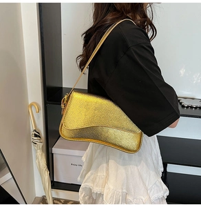 Detail of golden baguette bag with snakeskin texture and metallic finish on shoulder