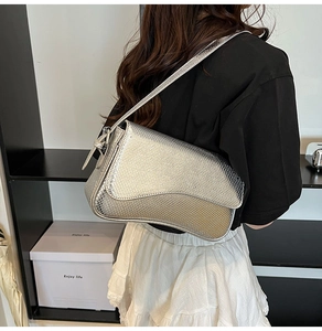 Close-up of silver snakeskin texture saddle bag worn on shoulder by a female model