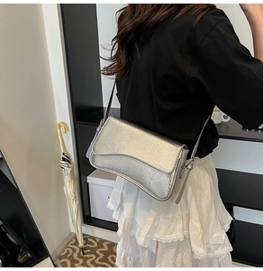 Detail of silver snake-pattern crossbody bag showing metallic texture and curved flap
