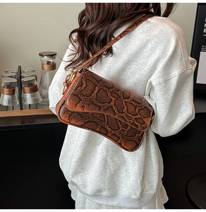 Detail of vintage snake print shoulder bag in brown PU leather with metal buckle