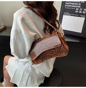Close-up of brown snakeskin pattern shoulder bag with adjustable strap and metal buckle