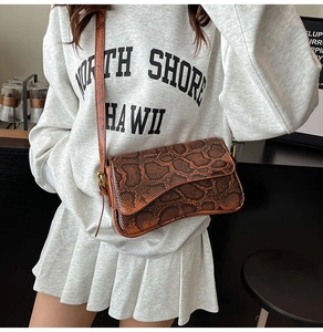 Detail of the brown snake print leather texture and flap closure on this crossbody bag