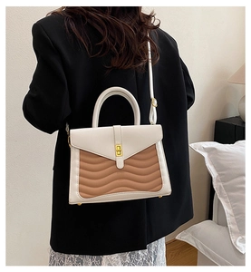 Detail of two-tone crossbody bag with wave texture and gold twist lock in use