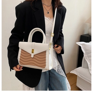 Detail of wave-patterned patchwork handbag with gold clasp on a fashion model