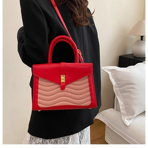 Detail of red and pink leather handbag with wavy quilting and golden twist lock