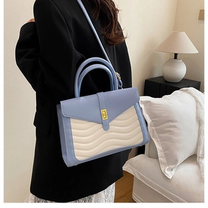 Detail of blue and beige handbag with wave stitching and gold twist lock closure