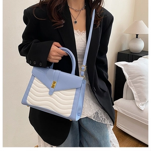 Detail showing wavy quilted stitching and golden twist lock on blue and white bag