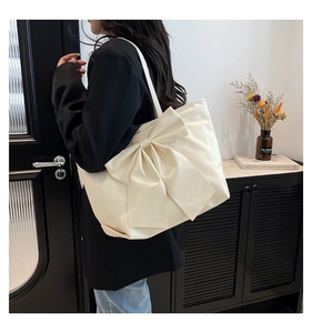 Detailansicht einer großen cremefarbenen Schleifen-Tasche mit glatter Satin-Stoffstruktur
