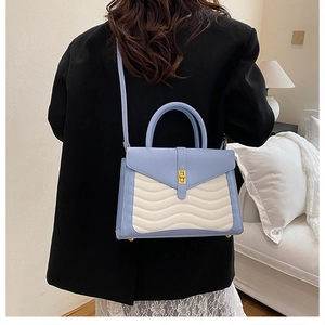 Close-up of wave textured blue and white handbag with golden metal twist lock and handle