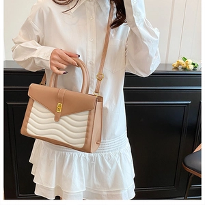 Detail of wave-quilted paneling and gold twist lock on women's chic crossbody bag