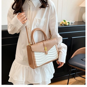 Detail of wave-quilted bicolor shoulder bag with golden lock on a vintage scene
