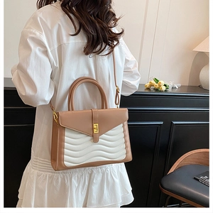 Detailed view of the wavy stitched texture and gold metal turn-lock on the leather handbag