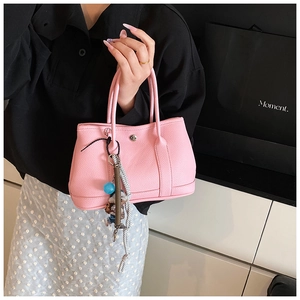 Détail du sac cabas en cuir rose avec breloque en corde tissée et fermoir en métal