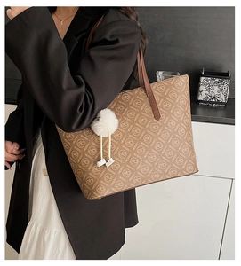 Close-up of brown tote bag with letter prints and a white fuzzy keychain decoration