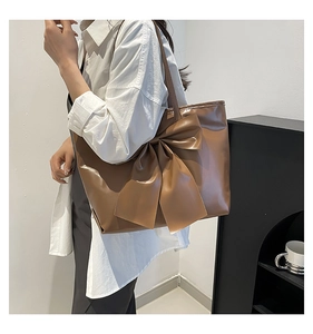 Detailansicht der großen Schleife an der braunen Shopper-Tasche aus glänzendem Leder