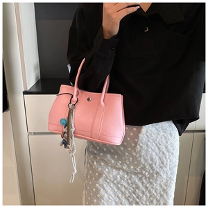 Sac seau en cuir rose à texture litchi avec breloque cheval porté par un mannequin