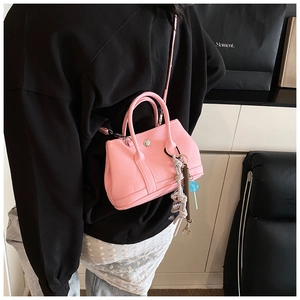 Sac seau rose en cuir grainé avec breloques mignonnes porté par un mannequin