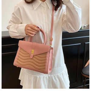 Detail of pink and khaki quilted handbag with golden buckle worn with white shirt