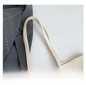 Detailansicht der verstärkten Griffe und feinen Textur der cremeweißen Shopper-Tasche