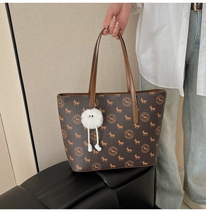 Detail of vintage brown leather tote bag with pony print and white plush charm