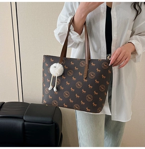 Detail of dark brown tote bag with horse monogram pattern and decorative plush charm