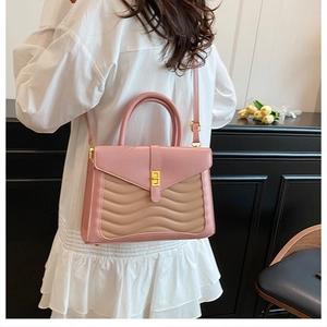 Detail of pink patchwork handbag with wave stitching and golden twist lock on model