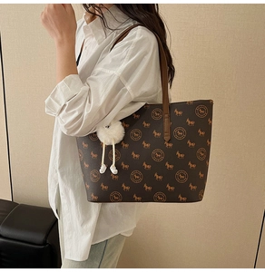 Brown tote bag with pony print and plush ball charm shown on model in a side view