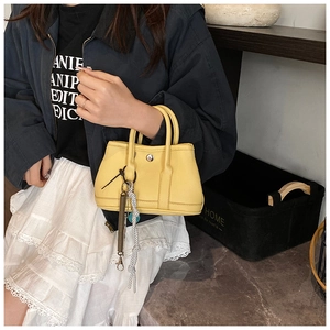 Gros plan d'un sac seau jaune avec texture cuir litchi et boucle métallique ronde