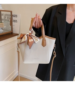 Détail du sac fourre-tout tissé beige avec bordure en cuir et foulard en soie décoratif