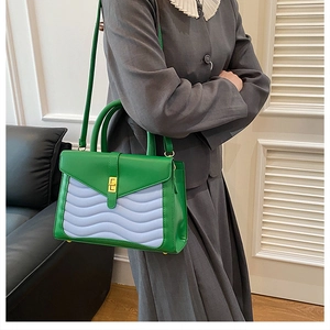 Close-up of wavy quilted handbag with gold buckle, green and lavender faux leather texture