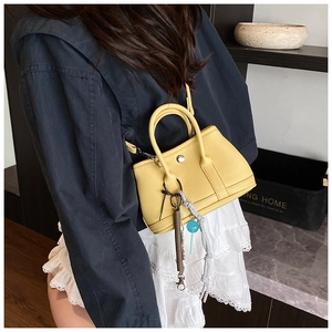 Détail du mini sac seau jaune en cuir litchi avec pendentifs et bandoulière réglable