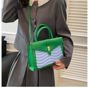 Model wearing a bright green and blue quilted handbag with wave stitching and gold lock