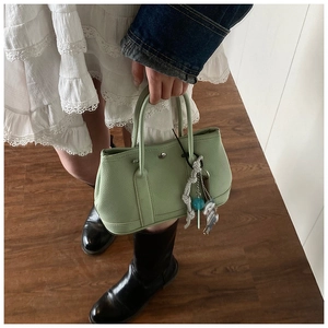 Gros plan sur un sac seau vert menthe en cuir grainé avec charms et poignées rondes