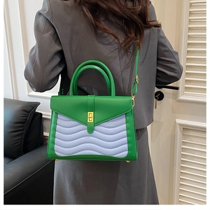 Detail of green and purple wave-quilted handbag featuring a gold metallic twist lock