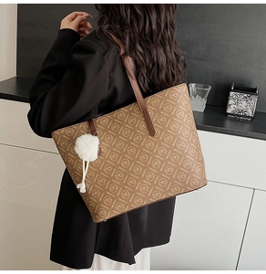 Detail of vintage monogram tote bag with white plush ball charm on a brown handle