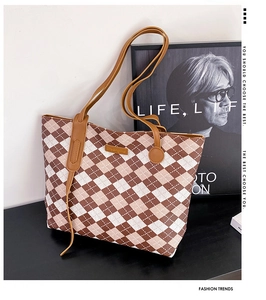 Detail of checkered tote bag with leather logo tag and thin brown shoulder strap