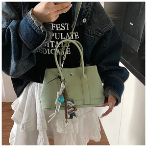 Detail van lichtgroene bucket bag met litchi patroon en schattige hondenhanger