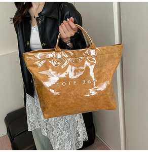 Dettaglio della borsa tote marrone lucida in Tyvek con scritta bianca TOTE BAG e texture