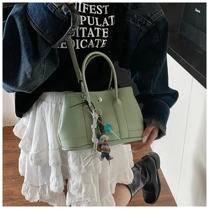 Détail du sac seau vert menthe en cuir grainé avec breloque ours et cordon tressé